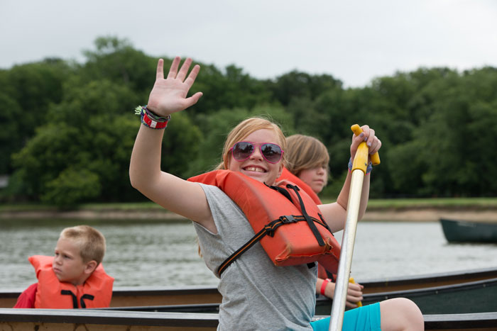 Child in a kayak waving at the camera